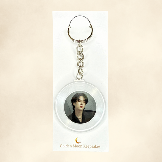 Keychain with a circular design featuring a portrait on a beige background