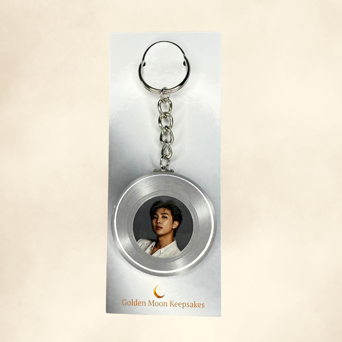 Keychain with a circular design featuring a portrait on a beige background