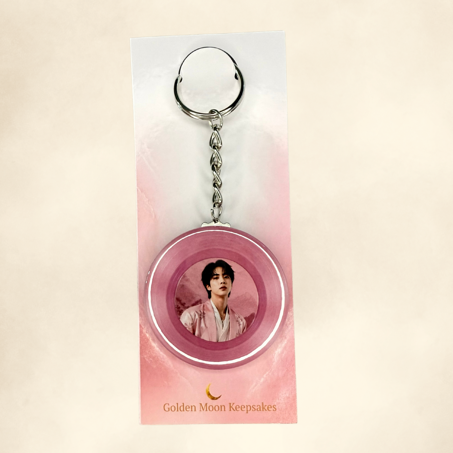 Keychain with a circular design featuring a person on a pink background, branded 'Golden Moon Keepsakes'.