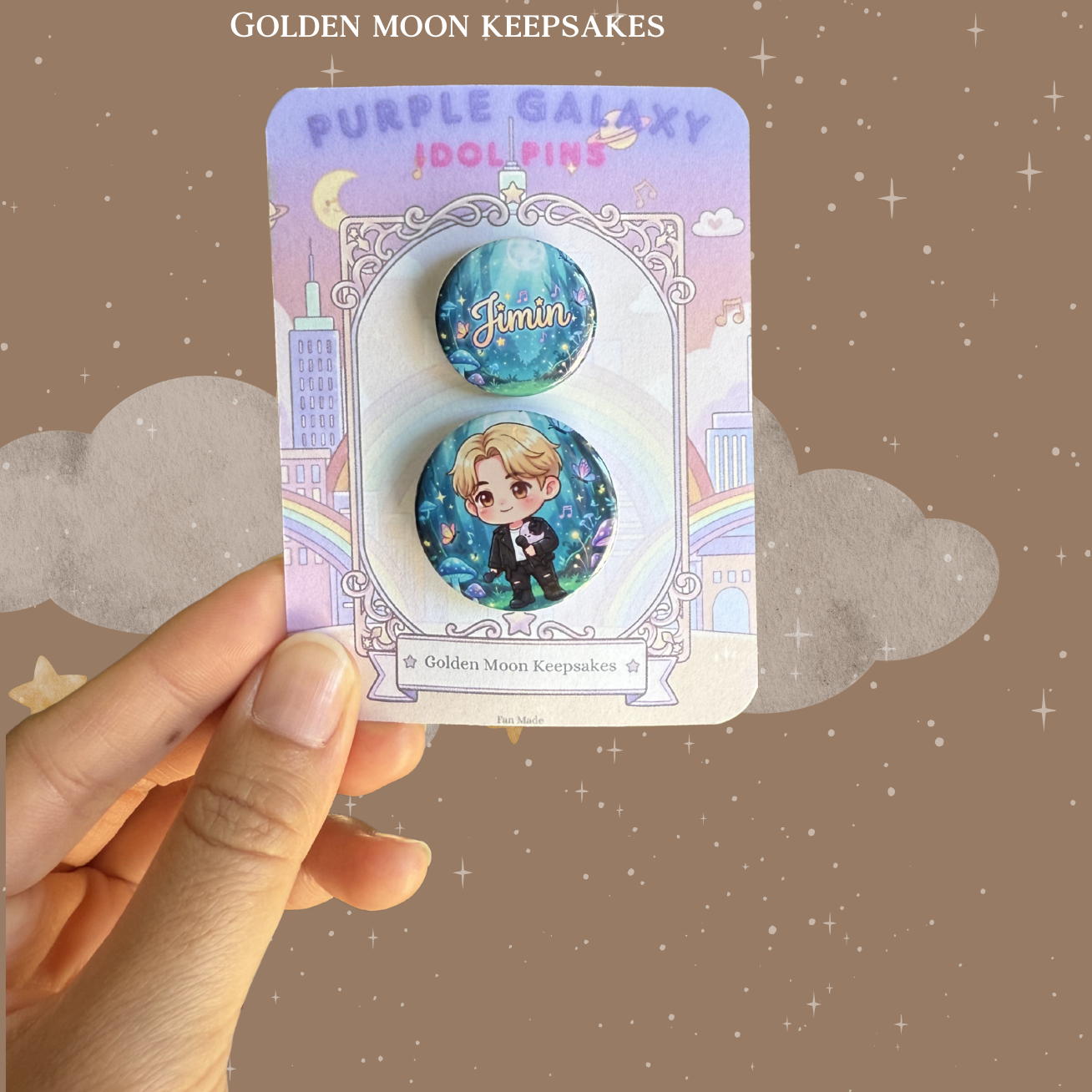 A two-piece pin set displayed on a "Golden Moon Keepsakes" card. The larger pin features a chibi character with blonde hair in a galaxy-inspired setting with stars and butterflies. The smaller coordinating pin displays the name "Jimin" in an elegant script over a deep blue and purple nebula background.