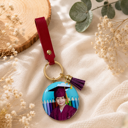 Graduation-themed keychain with a photo of a child on a textured surface with flowers.